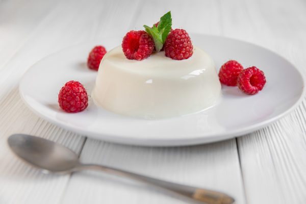 Panna cotta with raspberry, decorated with fresh mint on a white background